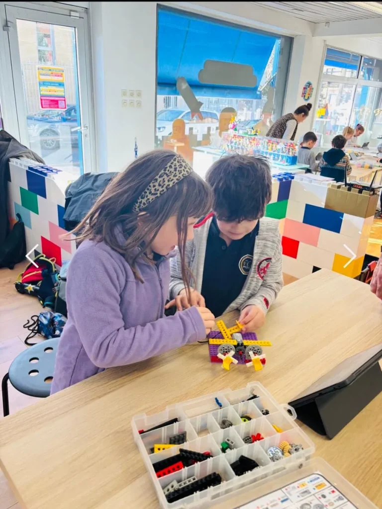 Deux élèves assemblant une maquette en briques lors d’un atelier de construction à l’École Val Saint André