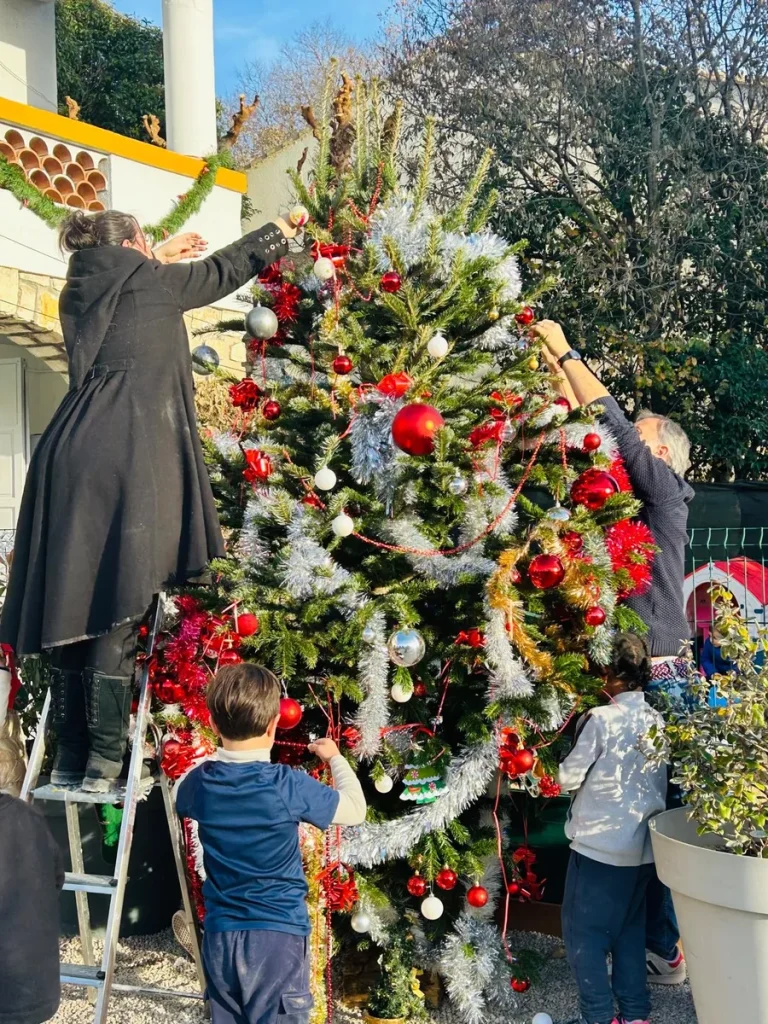 Élèves et enseignants décorant le grand sapin de Noël dans la cour de l’École Val Saint André